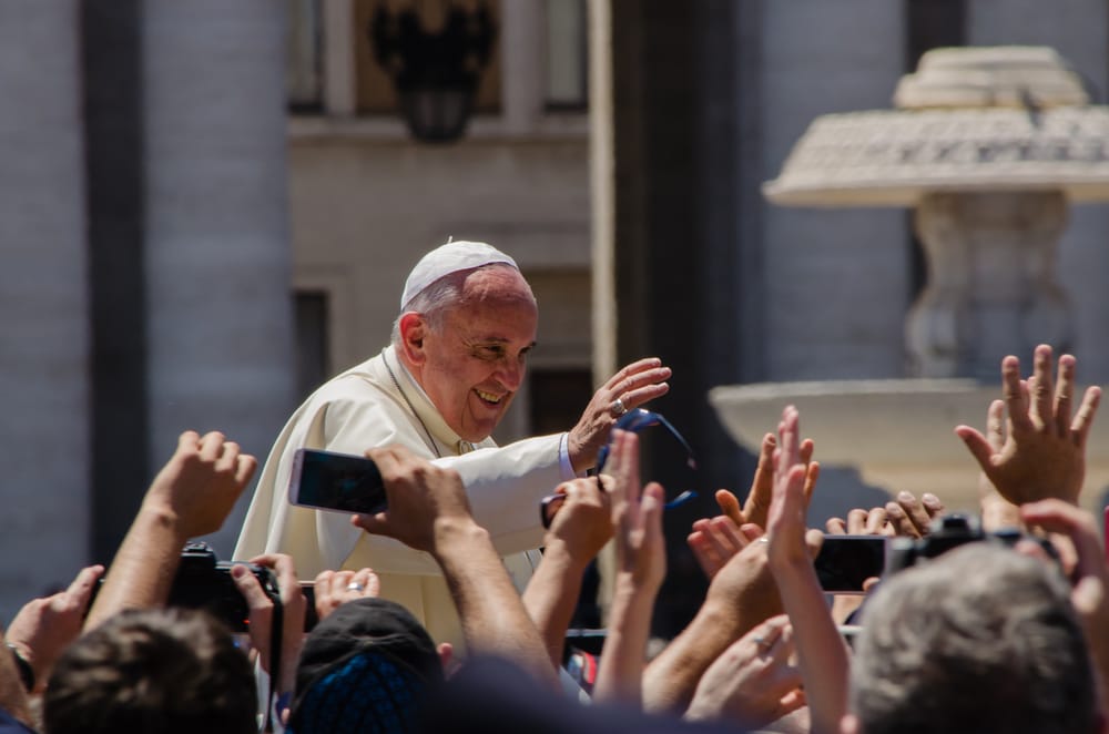 Among the grandeur of the Vatican, a pope intimately greets a gathering of people. Credit: Alfredo Borba